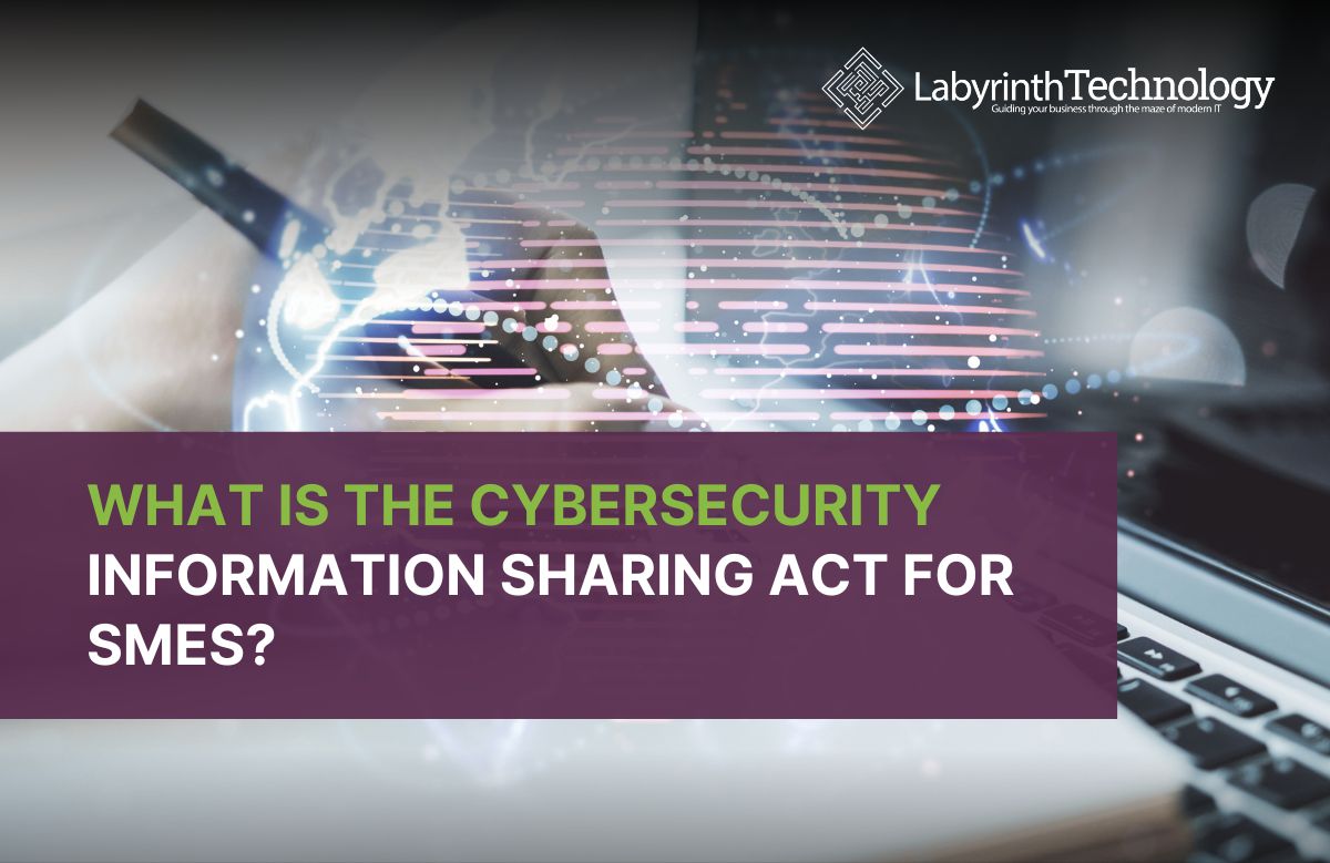 Double exposure of a person writing in a notebook with a laptop and digital world map overlay. the text reads "What is the Cybersecurity Information Sharing Act For SMEs?" The Labyrinth Technology logo is in the top right.