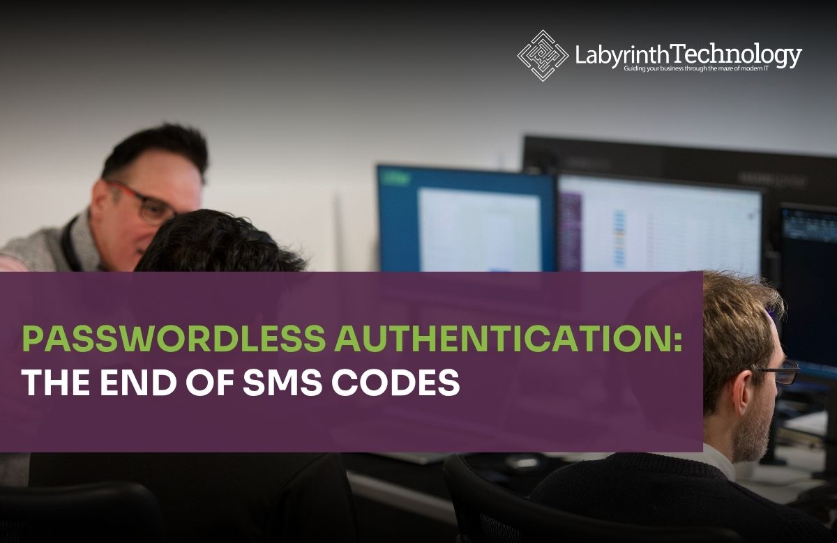3 men sitting infront of monitors working while one is explaining something to the others. The text in the bottom left reads "Passwordless Authentication: The End of SMS Codes" The Labyrinth Technology logo is in the top right.