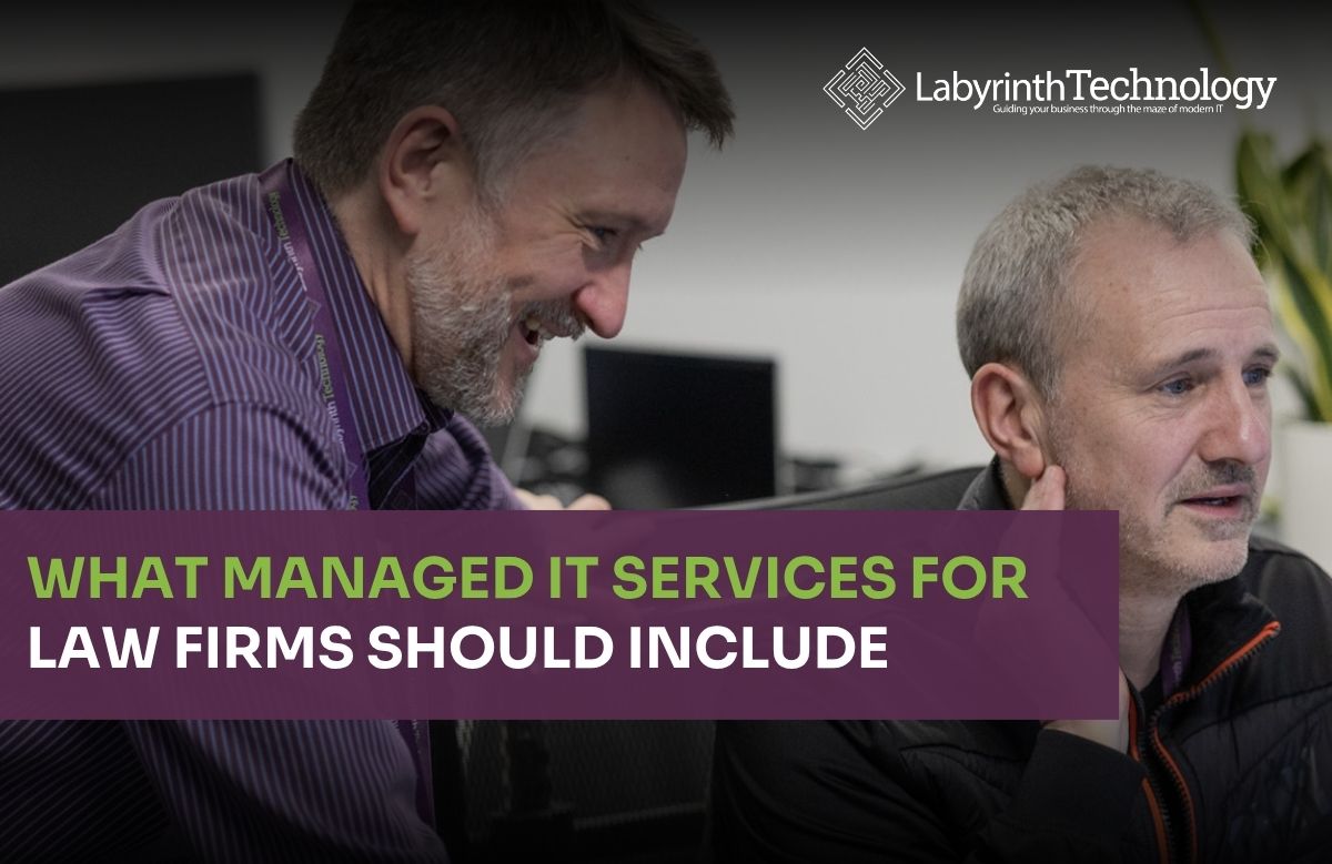 Two men looking at a monitors smiling and being jolly. The text in the bottom left reads"What Managed IT Services for Law Firms Should Include" The Labyrinth Technology logo is in the top right.
